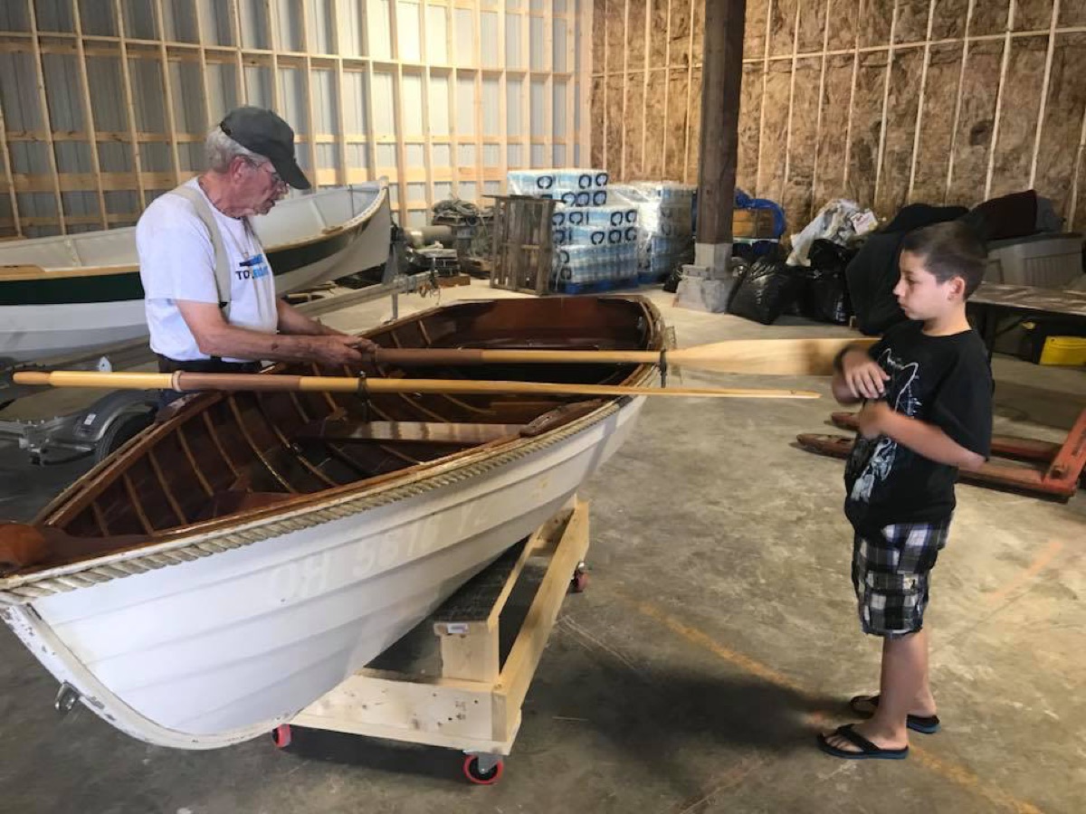 Adult and child beside a wooden boat