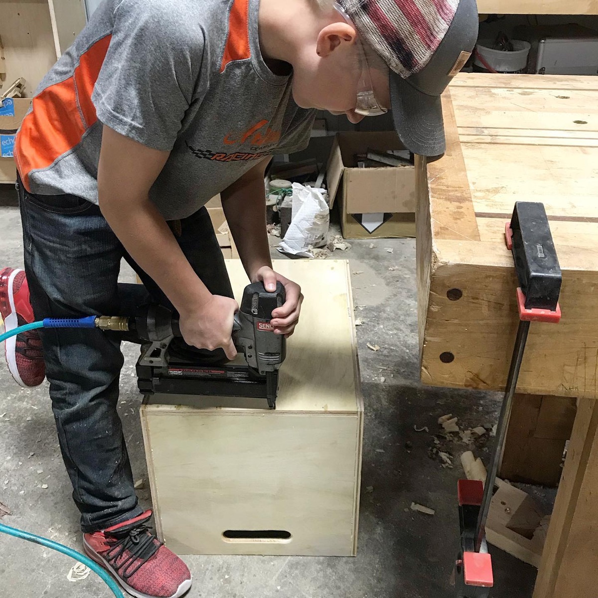 Student using a hand tool at a workbench