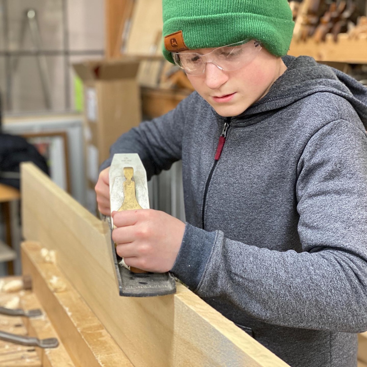 Student shaping wood with a hand tool