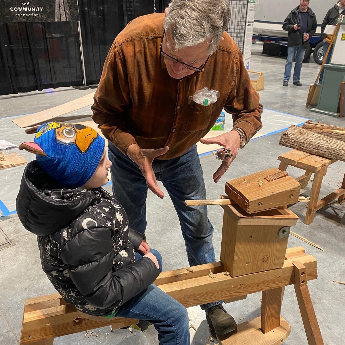 Mentor guiding a child at a woodworking bench