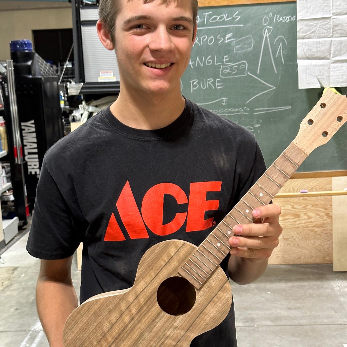 Student displaying a handmade string instrument