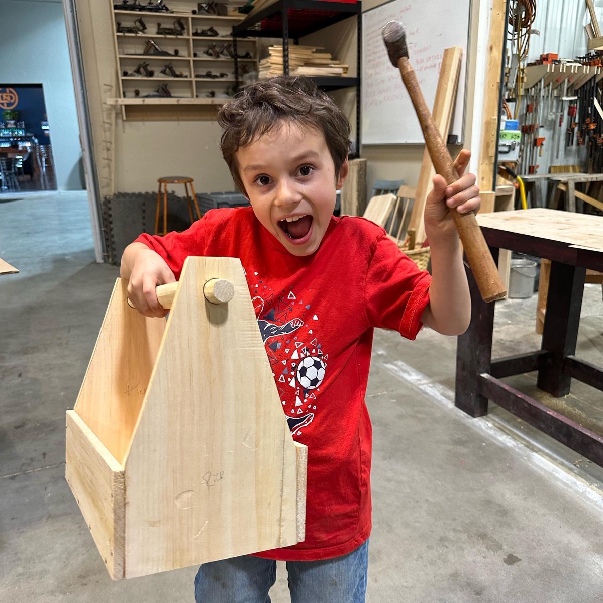 Student proudly holding a wooden tool tote
