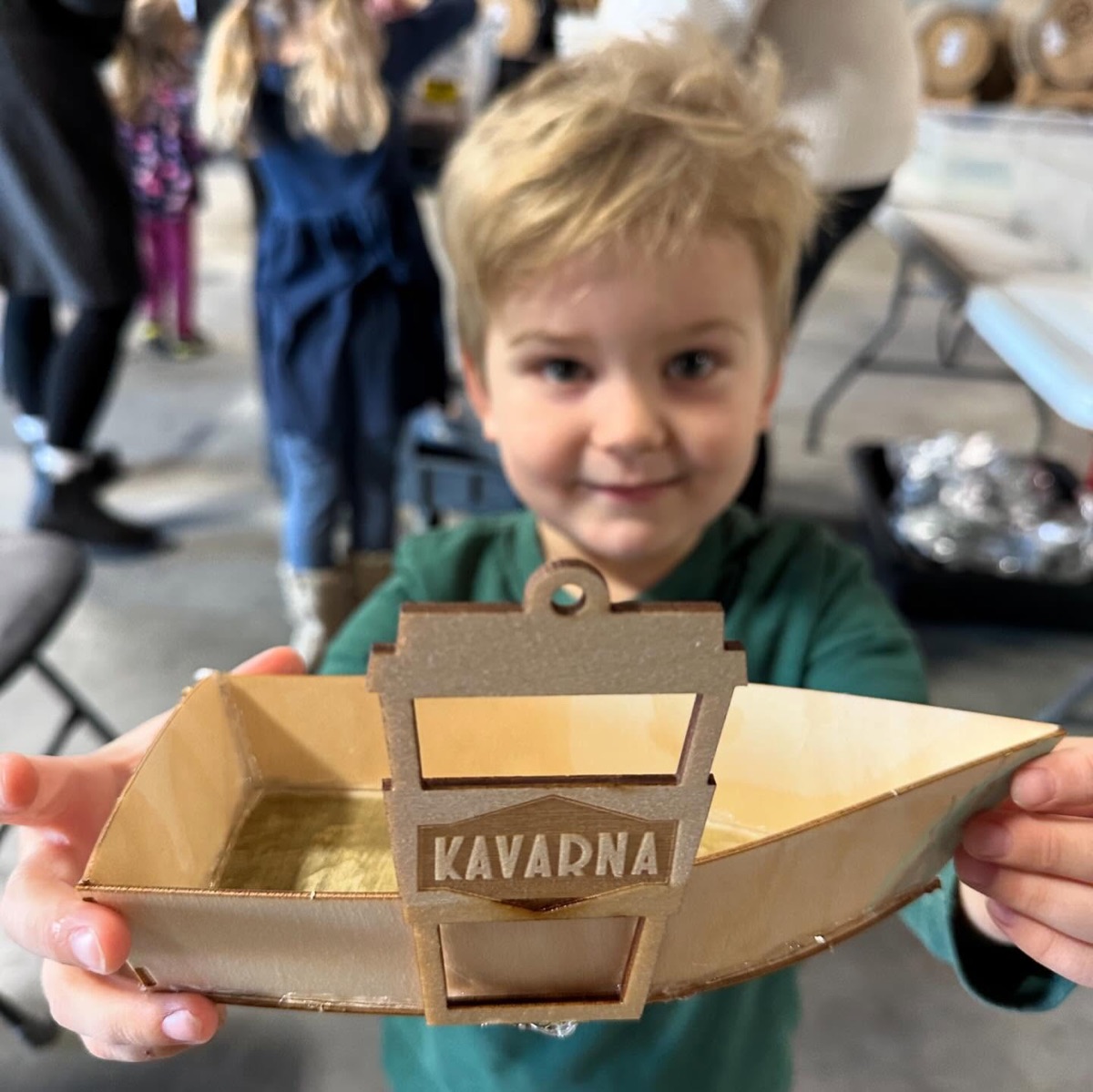 Child proudly holding a wooden boat model