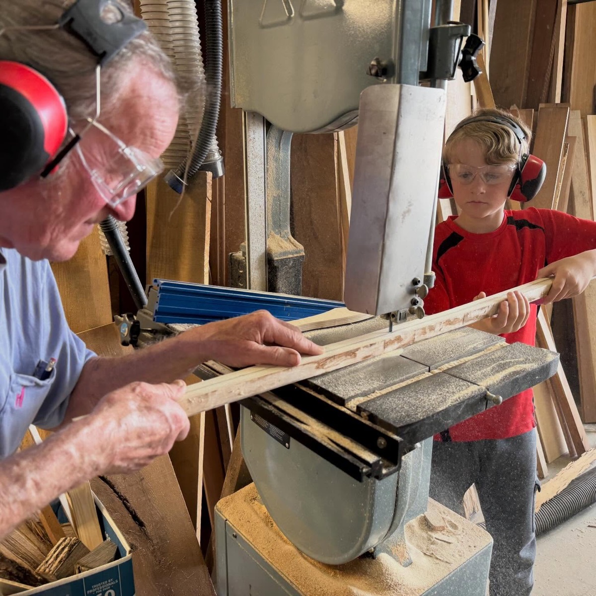 Mentor helping a student shape a wooden bow