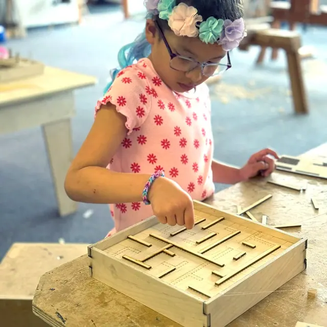 Child works on a handmade wooden maze project
