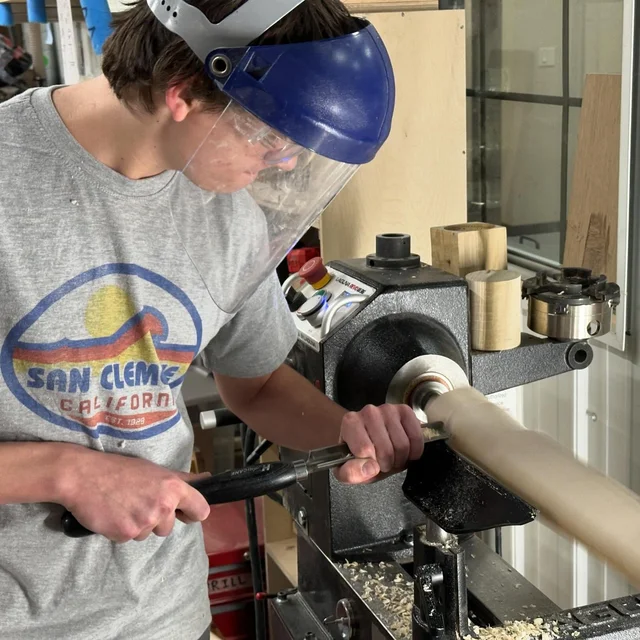 Hank shaping wood on a lathe with a turning tool