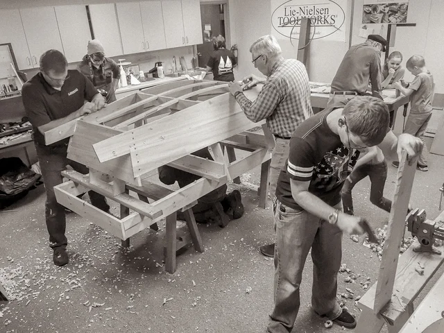 Children and adults working beside a wooden boat under construction at Brown County Library