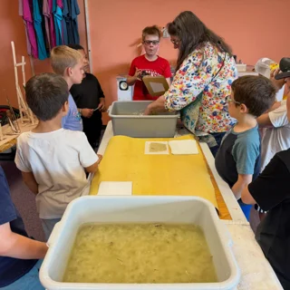 Papermaking instructor demonstrating the process to children at Hands On Deck