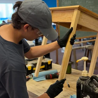 Hank working on a wooden table in the shop