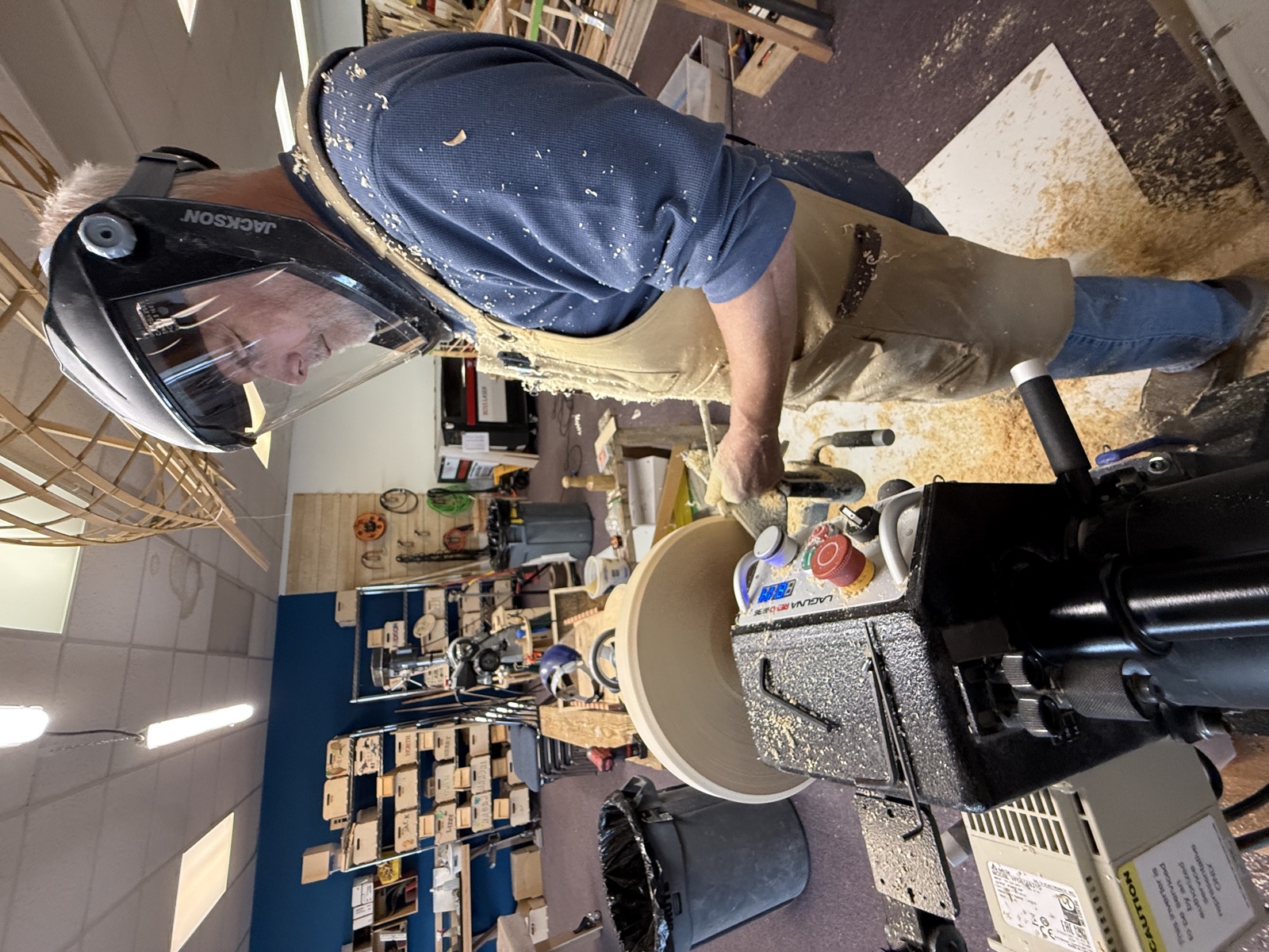 Casey turning wood on a lathe at Hands On Deck, wearing a protective face shield