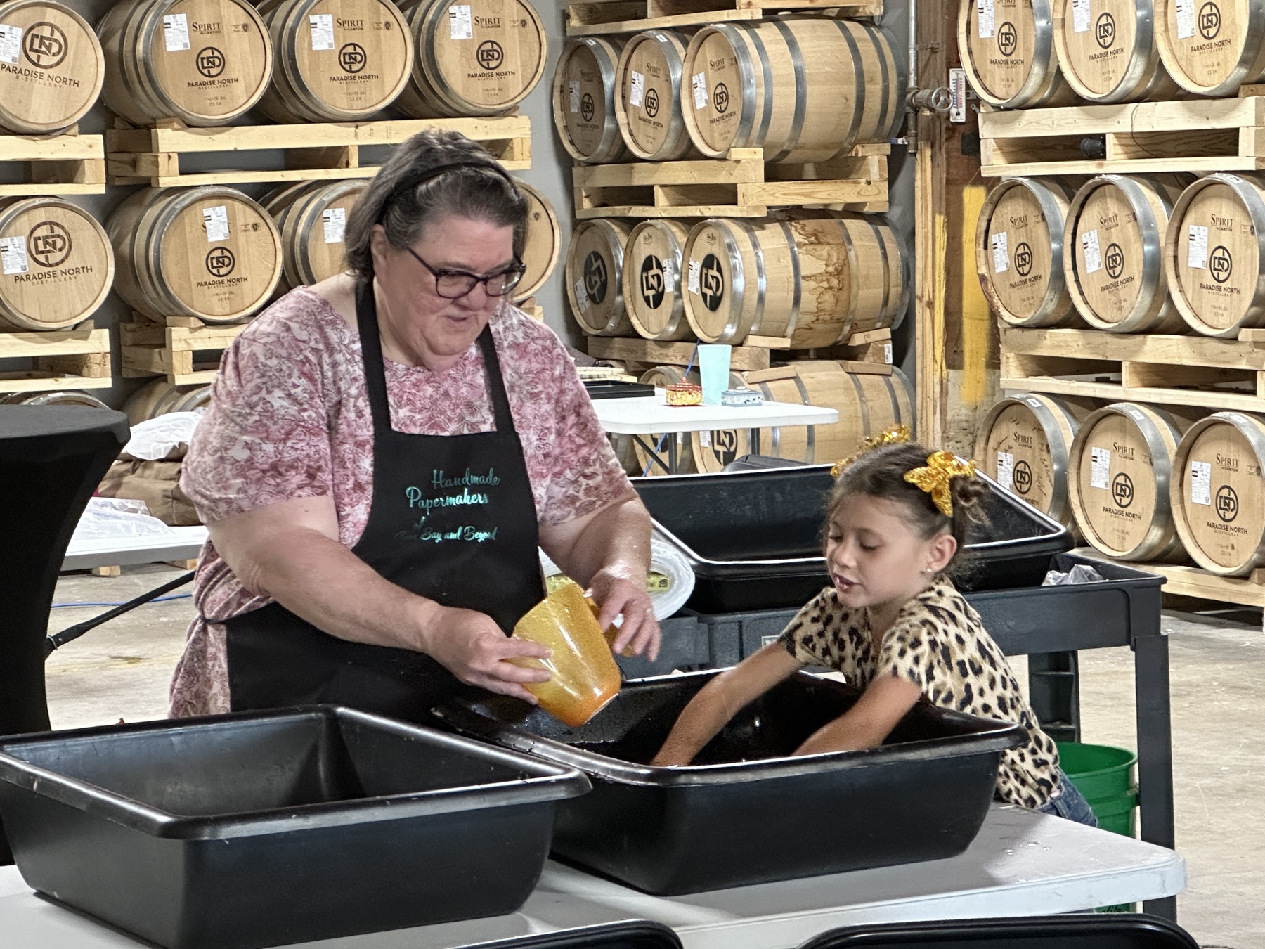 A papermaking instructor and a child working together at tubs of water during a hands-on workshop